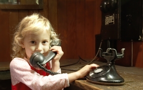Young Homestead visitor making a phone call on a 1927 telephone.