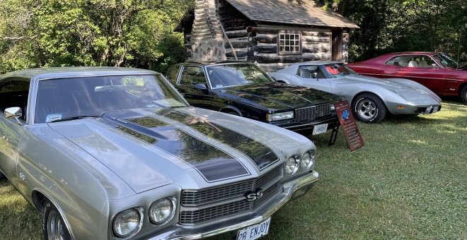 A row of antique and classic cars on display in front of the Fife Cabin
